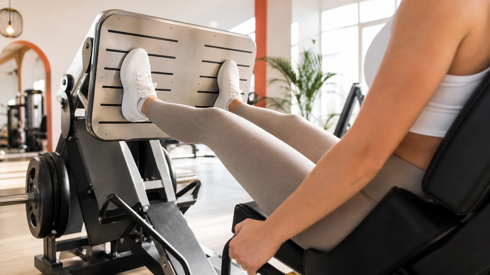 Benpressmaskin i ett ljust gym med viktmagasin och stor fotplatta