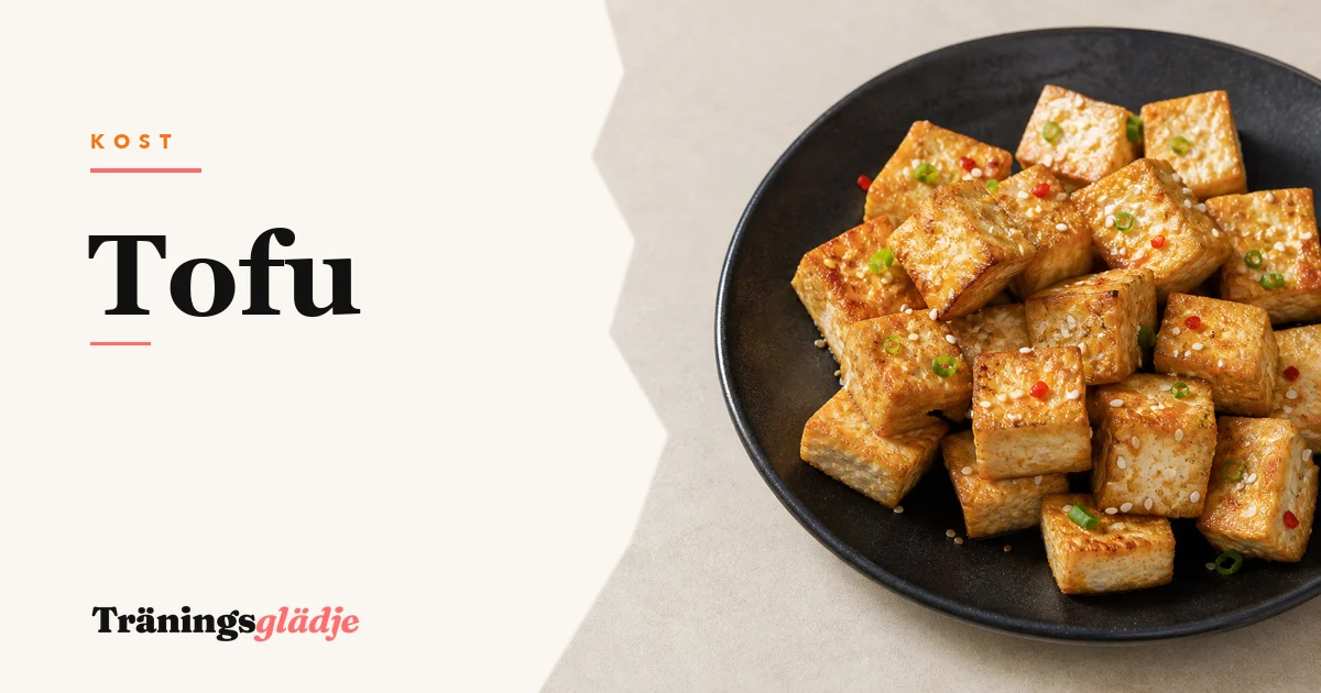 Gyllenstekta tofu-kuber på svart keramiktallrik med sesamfrön och vårlök, ätpinnar bredvid, ingen person synlig